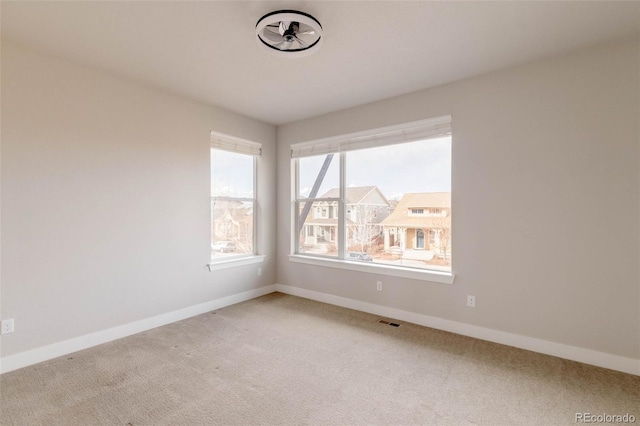 spare room featuring light carpet, visible vents, and baseboards