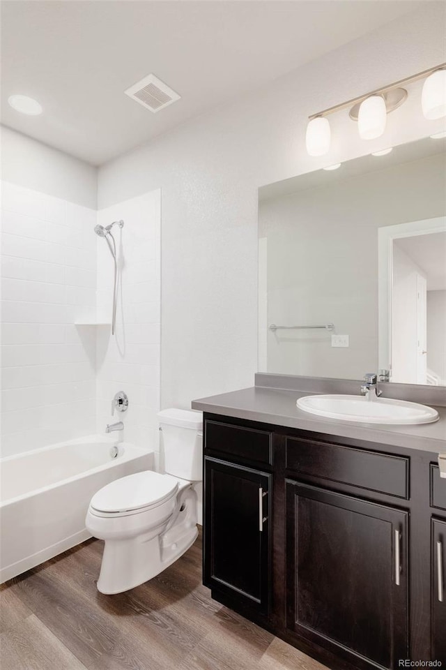 bathroom with bathtub / shower combination, visible vents, toilet, vanity, and wood finished floors