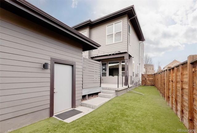 rear view of house with a yard and a fenced backyard