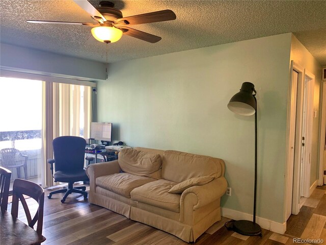 living room featuring wood-type flooring, a textured ceiling, a wealth of natural light, and ceiling fan