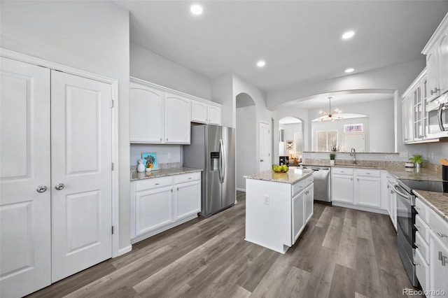 kitchen featuring stainless steel appliances, arched walkways, white cabinets, and dark wood-style flooring