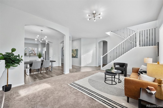 living area with arched walkways, carpet floors, stairs, a notable chandelier, and baseboards