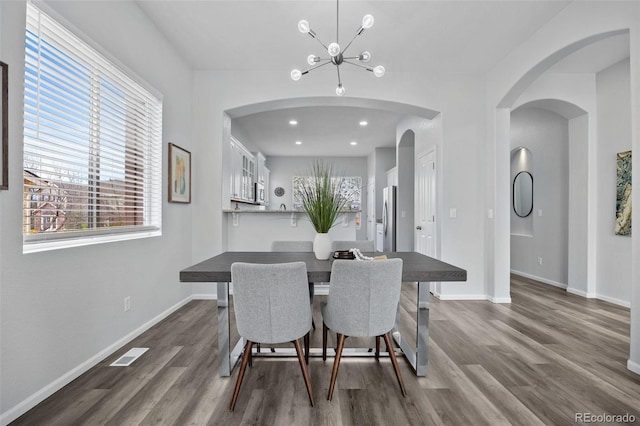 dining area with dark wood-style flooring, visible vents, baseboards, and an inviting chandelier