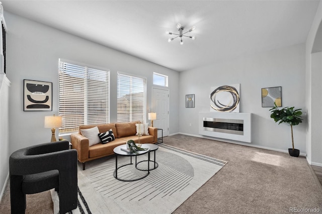 carpeted living room with a chandelier and baseboards