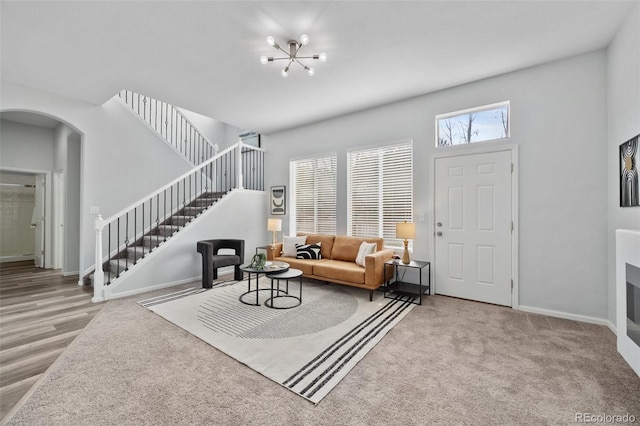 foyer entrance with arched walkways, a chandelier, wood finished floors, stairs, and baseboards