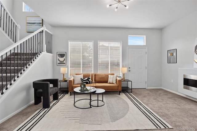living room featuring baseboards, carpet, and stairs