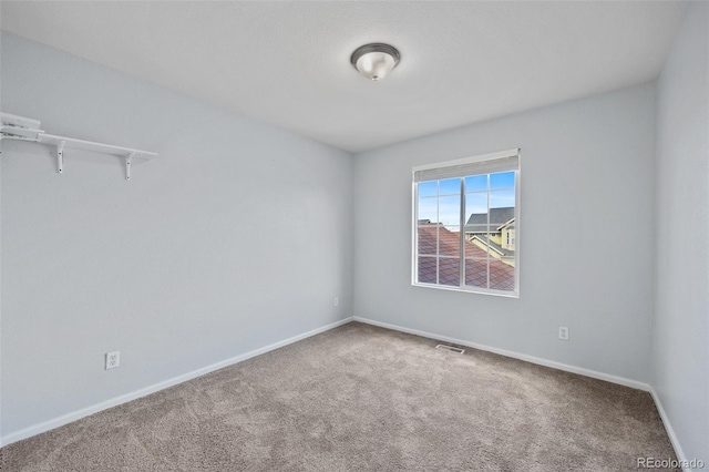 carpeted spare room featuring baseboards and visible vents