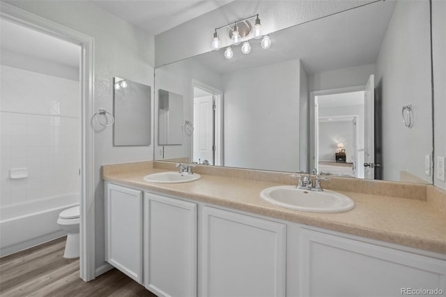 full bathroom with a sink, toilet, double vanity, and wood finished floors