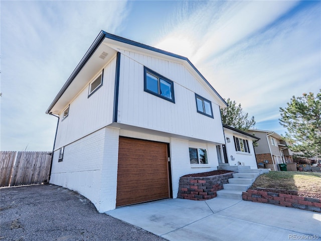 view of front of house featuring concrete driveway, an attached garage, fence, and brick siding