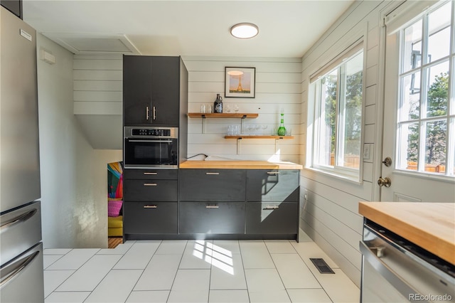 kitchen featuring light tile patterned floors, visible vents, wooden counters, open shelves, and appliances with stainless steel finishes