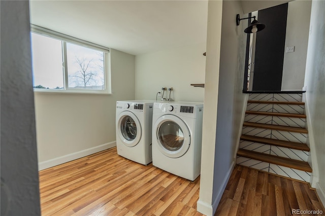 laundry area with wood finished floors, washing machine and dryer, and baseboards