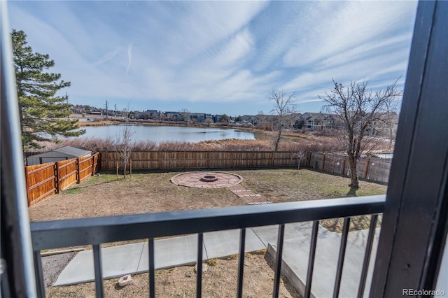 exterior space featuring an outdoor fire pit, a fenced backyard, and a water view