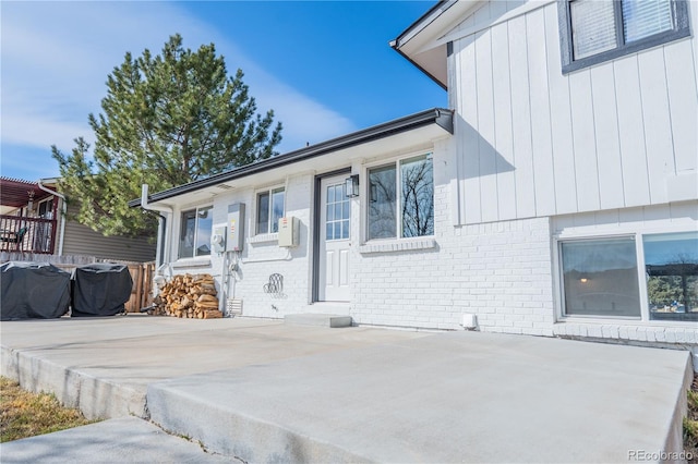 view of front of home featuring a patio and brick siding