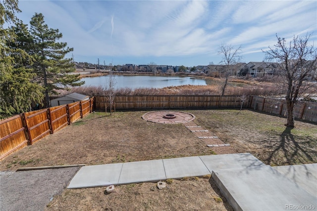 view of yard featuring a water view, a fenced backyard, and an outdoor fire pit