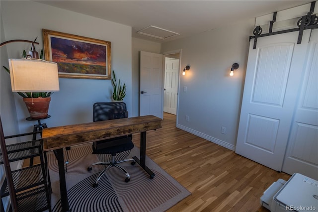 office featuring a barn door, wood finished floors, and baseboards