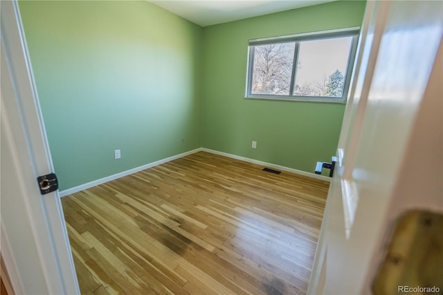 empty room with visible vents, baseboards, and wood finished floors