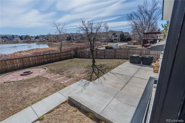 view of yard with a patio, a fire pit, a water view, and a fenced backyard