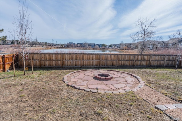 view of yard featuring a fenced backyard, a water view, and an outdoor fire pit