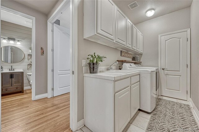 1410 Old Sequoia Ct, Franktown, CO 80116 - laundry area featuring cabinet space, washing machine and clothes dryer, baseboards, and light wood-style flooring