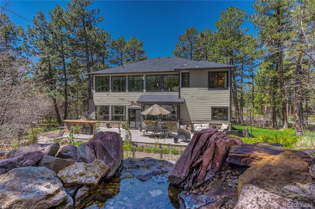 1410 Old Sequoia Ct, Franktown, CO 80116 - rear view of house with a patio area, stone siding, and roof with shingles