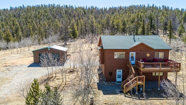 2418 Wells Fargo Cir, Jefferson, CO 80456 - back of property featuring a forest view, stairs, a deck, an outdoor structure, and roof with shingles