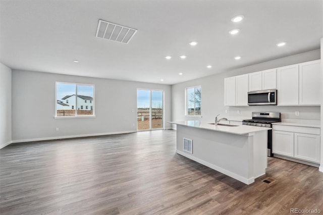 14424 Heritage Dr, Mead, CO 80504 - kitchen with appliances with stainless steel finishes, recessed lighting, open floor plan, wood finished floors, and white cabinets