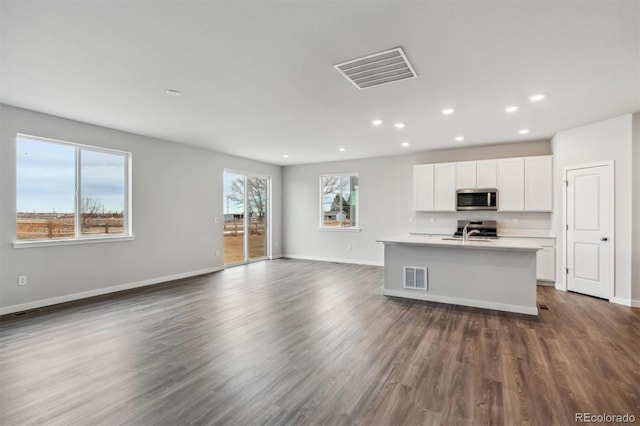 14424 Heritage Dr, Mead, CO 80504 - kitchen with open floor plan, recessed lighting, dark wood-style flooring, white cabinetry, and stainless steel microwave