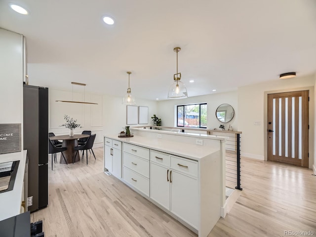 920 S Hudson St, Denver, CO 80246 - kitchen featuring freestanding refrigerator, light wood-type flooring, a center island, white cabinetry, and light countertops