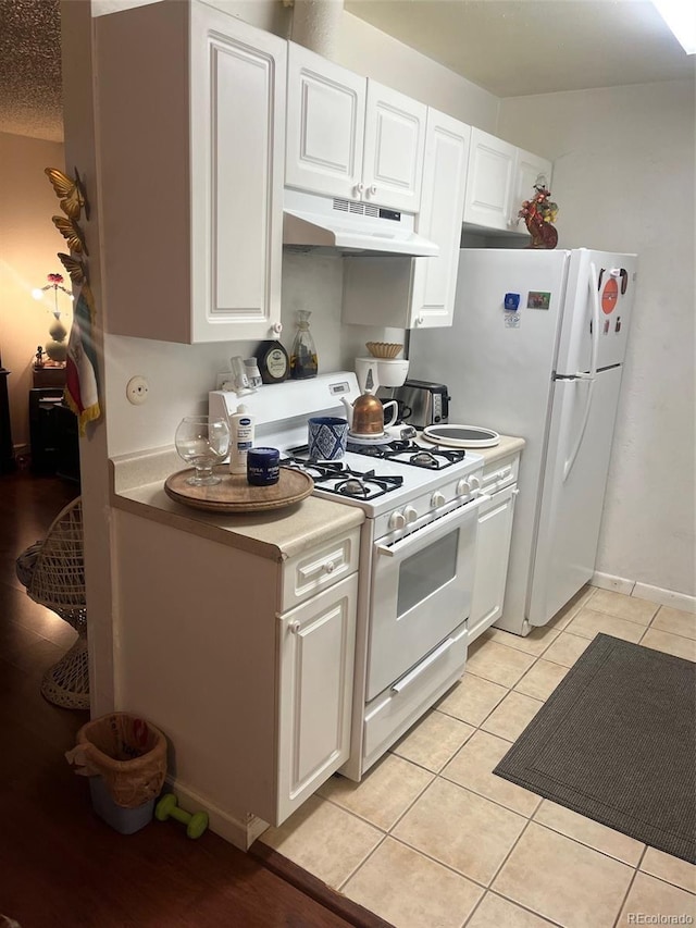 kitchen featuring light tile patterned floors, white cabinets, a textured ceiling, and gas range gas stove