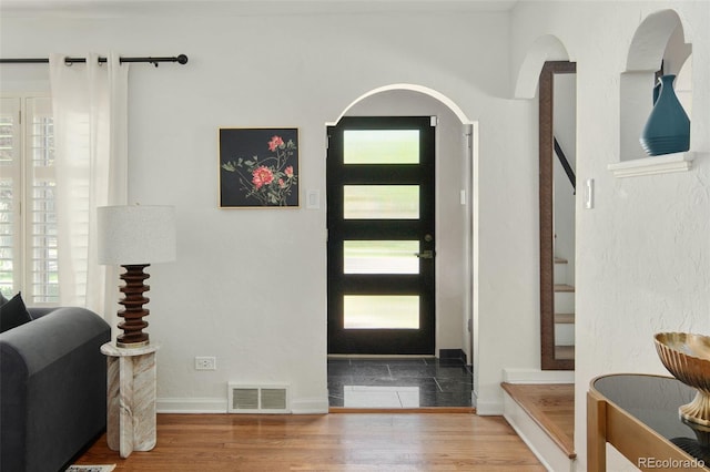 foyer entrance featuring wood finished floors, stairs, and baseboards