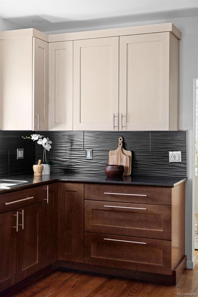 kitchen featuring decorative backsplash, dark countertops, dark wood-style flooring, and a sink