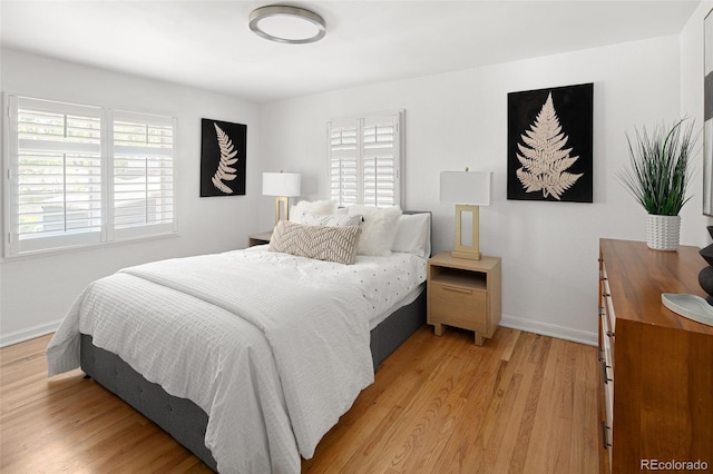 bedroom featuring multiple windows, baseboards, and light wood-type flooring