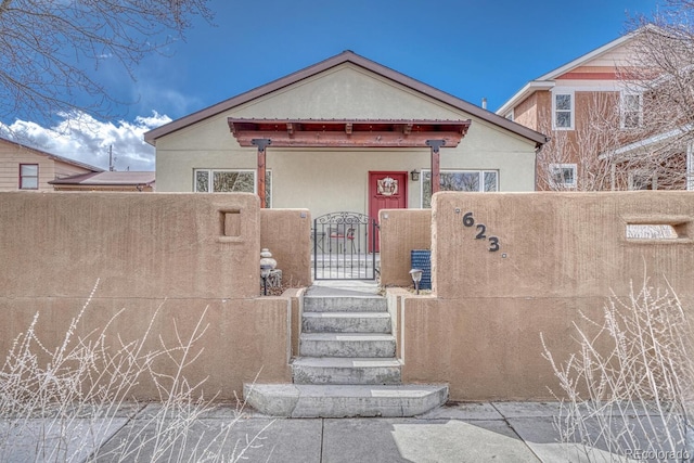 view of front of house with a fenced front yard, a gate, and stucco siding