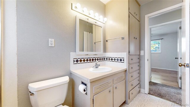 bathroom featuring toilet, decorative backsplash, vanity, and hardwood / wood-style floors