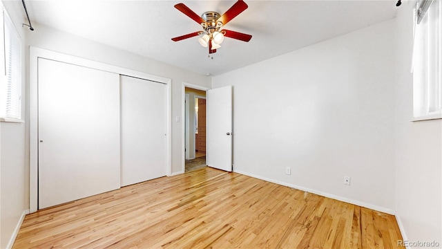 unfurnished bedroom featuring a closet, ceiling fan, multiple windows, and light hardwood / wood-style flooring