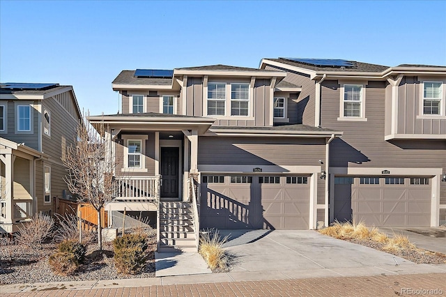 view of front of property featuring driveway, board and batten siding, a garage, and solar panels