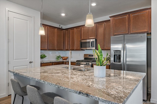 kitchen with backsplash, light stone counters, stainless steel appliances, and a sink