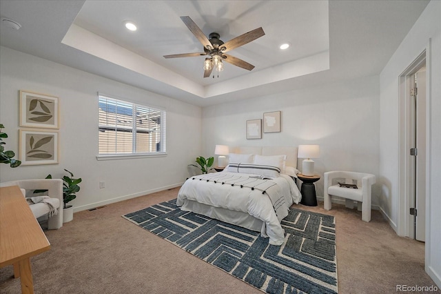 carpeted bedroom with a tray ceiling, recessed lighting, visible vents, a ceiling fan, and baseboards