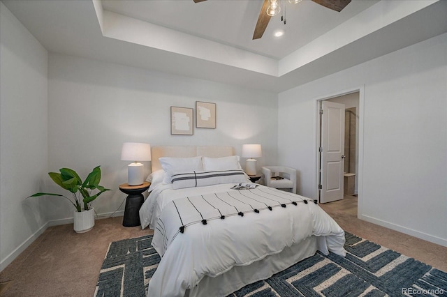 bedroom featuring a tray ceiling, carpet, a ceiling fan, and baseboards