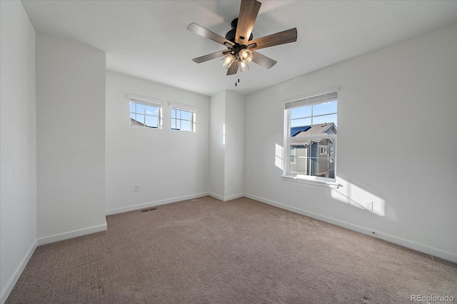 carpeted empty room with visible vents, ceiling fan, and baseboards