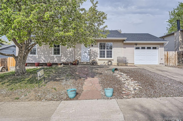 view of front of home featuring driveway, roof with shingles, a garage, brick siding, and fence