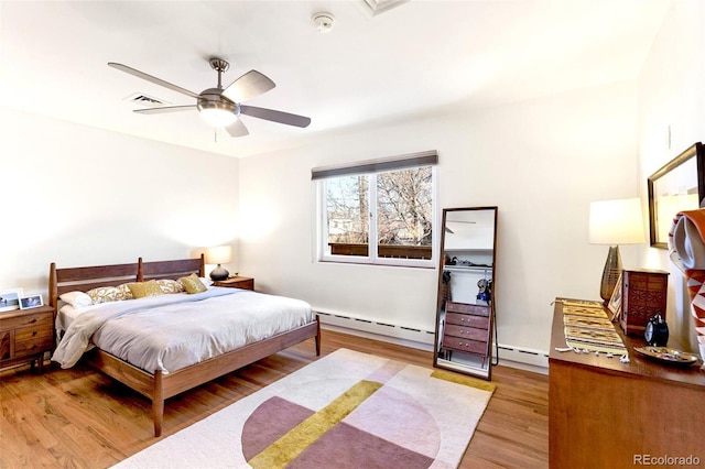 bedroom featuring a baseboard heating unit, ceiling fan, and light hardwood / wood-style flooring