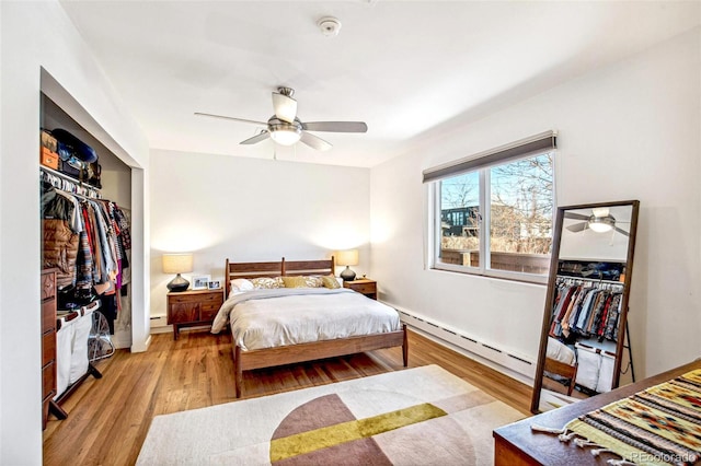 bedroom with a baseboard radiator, light hardwood / wood-style floors, a closet, and ceiling fan