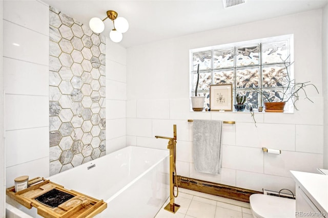 bathroom featuring toilet, tile walls, vanity, a bathing tub, and tile patterned flooring