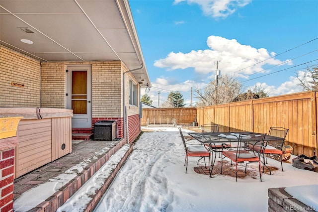 snow covered patio with central AC and a hot tub