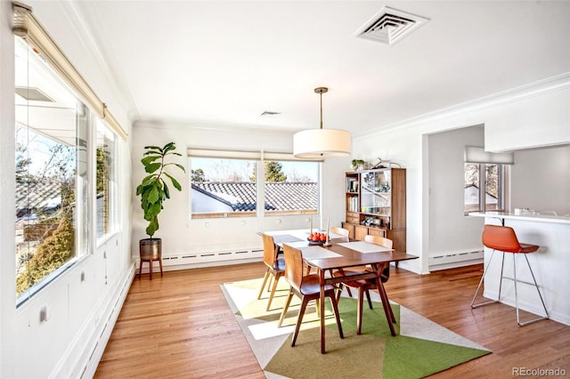 dining area with a baseboard radiator, visible vents, baseboards, ornamental molding, and light wood-type flooring