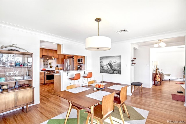 dining space with visible vents, baseboard heating, ornamental molding, light wood-type flooring, and baseboards