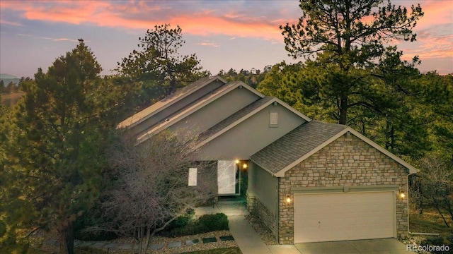 view of front of property featuring a garage, stone siding, and concrete driveway