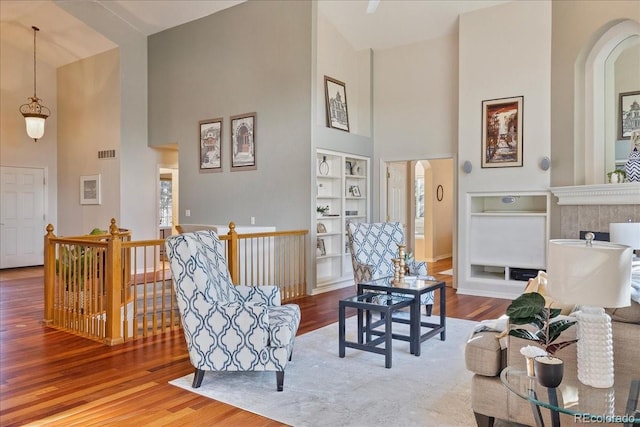 living area featuring visible vents, built in features, wood finished floors, and an upstairs landing