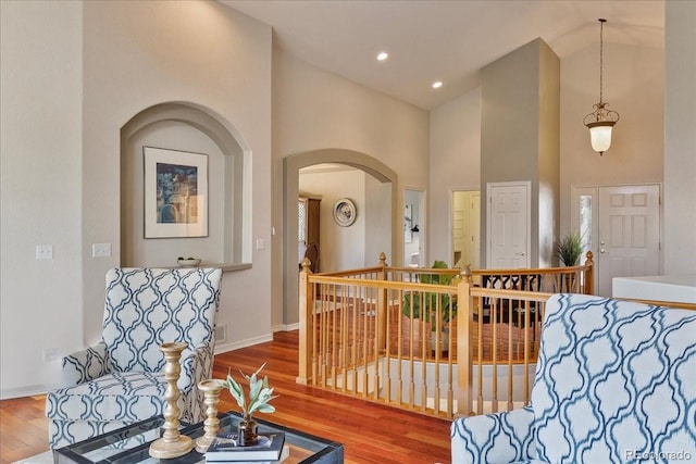 entryway with arched walkways, high vaulted ceiling, recessed lighting, wood finished floors, and baseboards